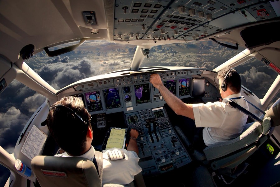 Airline crew flying a widebody jet above the clouds
